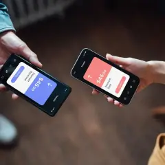Dwie osoby dokonują płatności przez telefon. Jedna pokazuje "Payment Received $45.00", druga "Payment Sent $45.00". Czy Revolut jest bezpieczny? Tak, transakcje są szyfrowane.