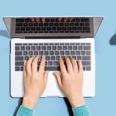 Dłonie piszą na laptopie, a obok leżą skarbonki. Zastanawiasz się, ile cyfr ma numer konta?