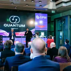 Prezentacja Quantum creotech na GPW. Na ekranie widać notowania i logo firmy.