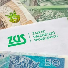 Kiedy ZUS wypłaca L4, pieniądze wreszcie się pojawiają. Koperta z logo ZUS na tle polskich banknotów.