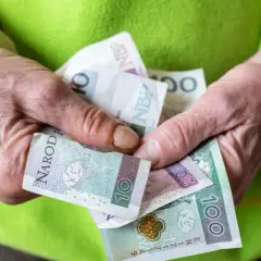 Dłonie trzymają polskie banknoty. Zastanawiasz się, ile wynosi renta socjalna?