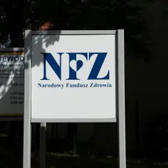 Tablica z logo NFZ i napisem "Narodowy Fundusz Zdrowia". Obok tablica z informacją o kontrakcie i kosztach inwestycji.