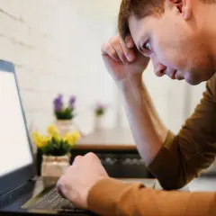Mężczyzna zamyślony nad laptopem, zastanawia się, bdo co to.