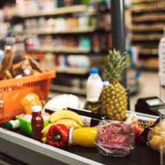 Koszyk z zakupami na taśmie w supermarkecie. Owoce, warzywa, makaron i napoje – typowe produkty FMCG, czyli szybko zbywalne towary.