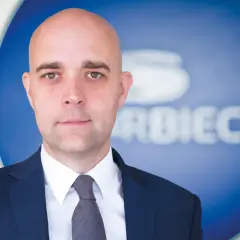 Łysy mężczyzna w garniturze na tle logo Skarbiec TFI. Analiza notowań.