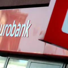 Logo eurobank na czerwonym tle. Obok widoczny fragment czerwonego kwadratu z białym znakiem.