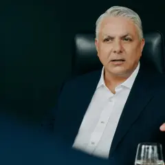 Mężczyzna w garniturze, członek Erste Group, gestykuluje podczas rozmowy.