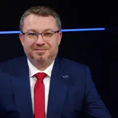 Mężczyzna w garniturze i czerwonym krawacie, z przypinką z logo. Może to być prezes Polimex Akcje.