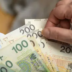 Dłoń trzyma polskie banknoty 100 i 200 zł. Wkrótce renta wdowia 2026.