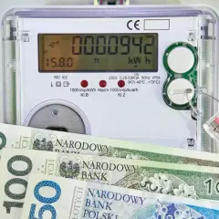 Licznik energii elektrycznej z banknotami 100 zł. Zastanawiasz się, jaka będzie cena prądu 2026 za 1 kWh?