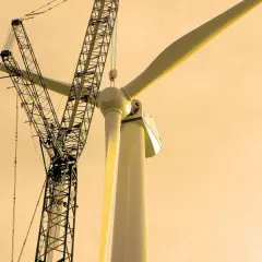 Budowa turbiny wiatrowej, kluczowy element OZE, w tle potężny dźwig.