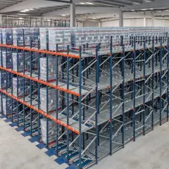 Duże regały magazynowe z towarami ułożonymi zgodnie z zasadą fifo. Towary na rolkach, gotowe do wysyłki.