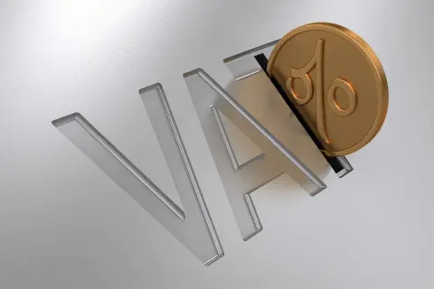 Złota moneta z symbolem procentu wpada do litery "A" w napisie "VAT".