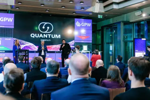 Prezentacja Quantum creotech na GPW. Na ekranie widać notowania i logo firmy.