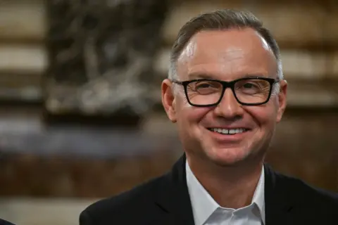 Uśmiechnięty mężczyzna w okularach, w garniturze. Czyżby planował już emeryturę prezydencką?