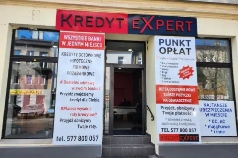 Elegancka fasada biura "Kredyt Expert" z banerami informującymi o usługach kredytowych i płatnościach.