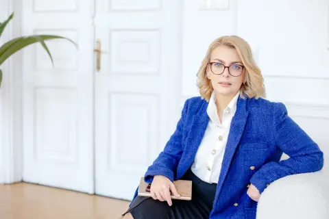 Kobieta w okularach i niebieskiej marynarce trzyma notatnik. Planujesz otwarcie firmy w 2025? Sprawdź dostępne dotacje!