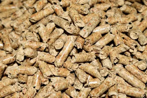 Zbliżenie na stos drobnych, cylindrycznych granulek drewna. Wygląda na to, że brakuje pelletu do ogrzewania domu.