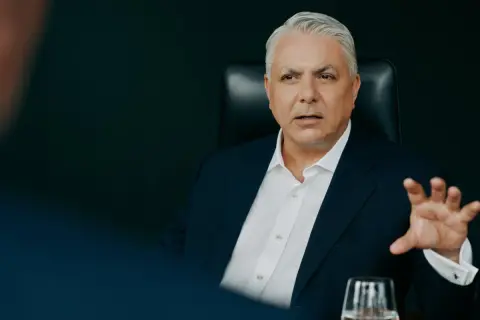 Mężczyzna w garniturze, członek Erste Group, gestykuluje podczas rozmowy.