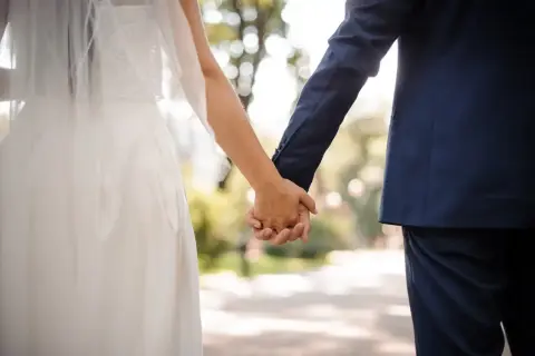 Para młoda trzymająca się za ręce, w tle park. To idealny moment na urlop okolicznościowy.