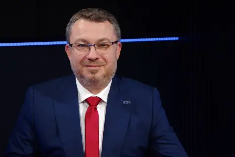 Mężczyzna w garniturze i czerwonym krawacie, z przypinką z logo. Może to być prezes Polimex Akcje.