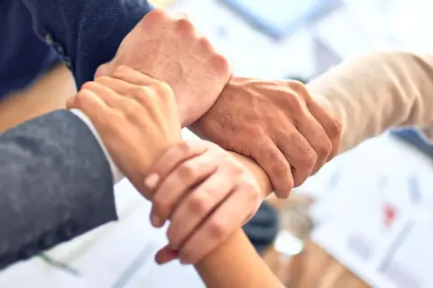 Dłonie splecione w geście współpracy, symbolizujące siłę networkingu i wspólnego celu.