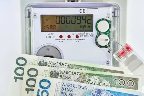Licznik energii elektrycznej z banknotami 100 zł. Zastanawiasz się, jaka będzie cena prądu 2026 za 1 kWh?