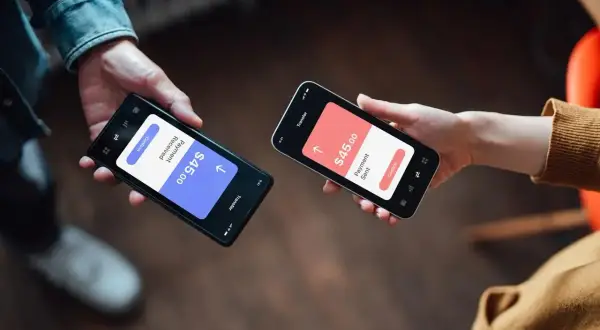 Dwie osoby dokonują płatności przez telefon. Jedna pokazuje "Payment Received $45.00", druga "Payment Sent $45.00". Czy Revolut jest bezpieczny? Tak, transakcje są szyfrowane.