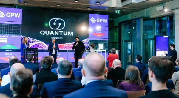 Prezentacja Quantum creotech na GPW. Na ekranie widać notowania i logo firmy.