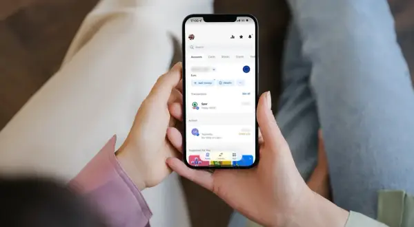 Dłonie trzymają smartfon z aplikacją bankową, gdzie widać ostatnie transakcje, w tym zakup w Sparze. Można sprawdzić saldo i historię, unikając debetu.