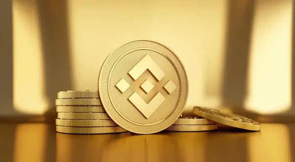 Złote monety z symbolem BNB, ułożone w stosy na błyszczącym, złotym tle.