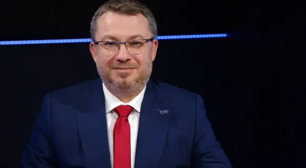 Mężczyzna w garniturze i czerwonym krawacie, z przypinką z logo. Może to być prezes Polimex Akcje.