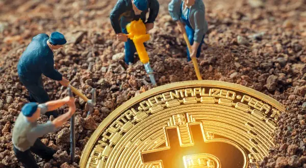 Figurki górników pracują przy kopaniu kryptowalut, używając kilofów i młota pneumatycznego, aby wydobyć złoty Bitcoin z ziemi.