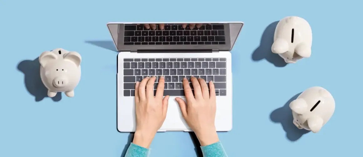 Dłonie piszą na laptopie, a obok leżą skarbonki. Zastanawiasz się, ile cyfr ma numer konta?