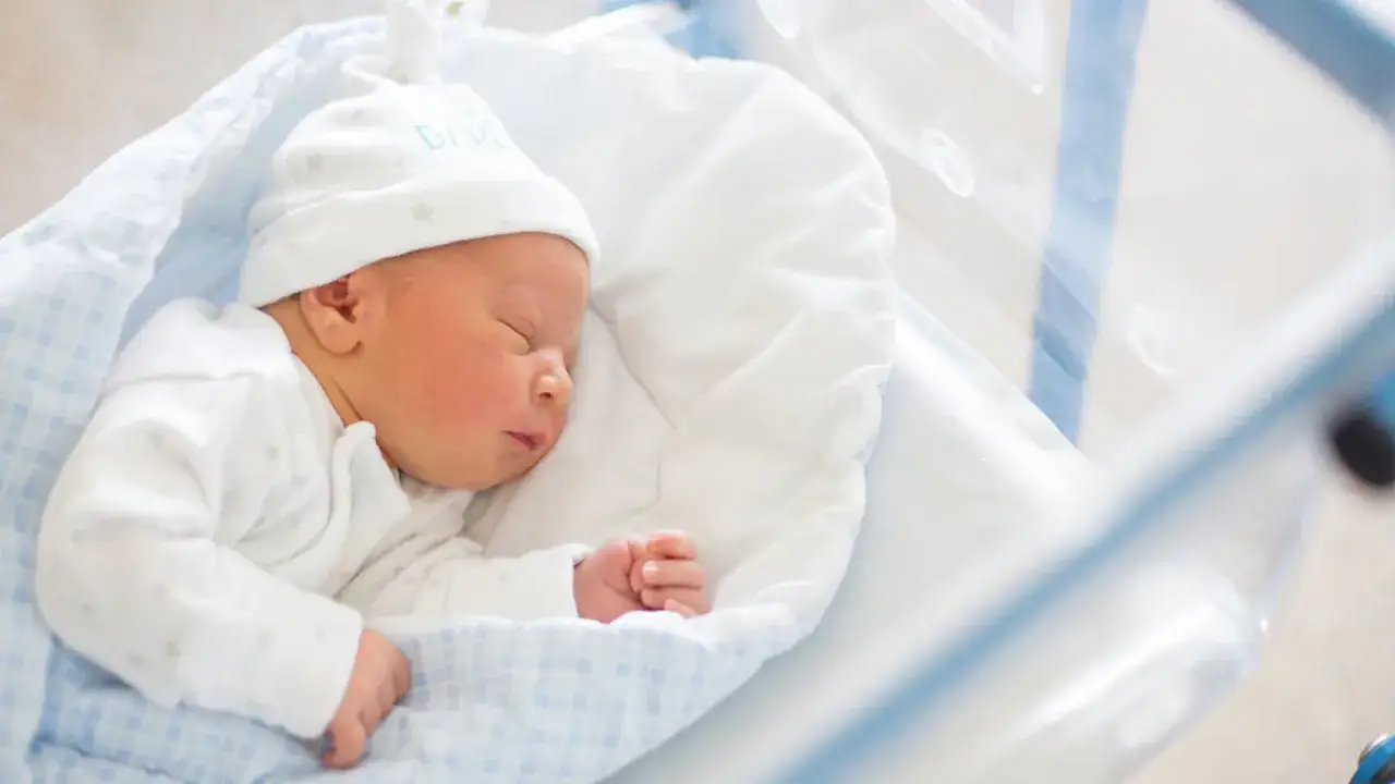 Śpiący noworodek w czepku z napisem 