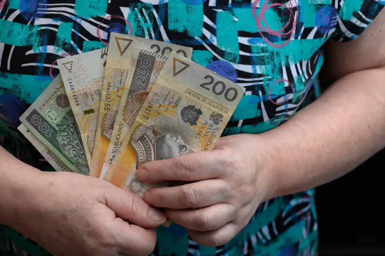 Dłonie trzymają polskie banknoty. Może to być część oszczędności na rentę wdowią 2026.