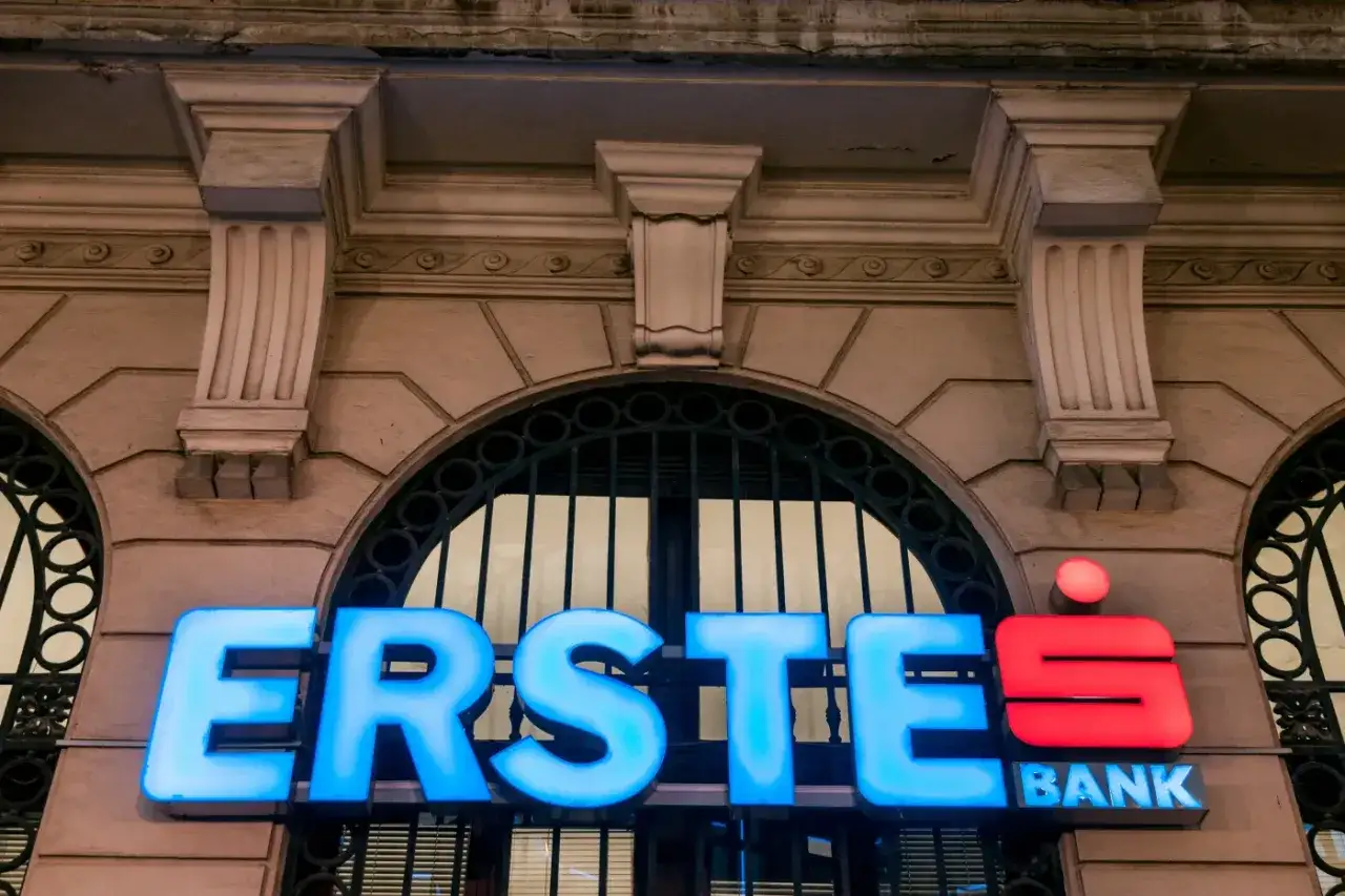 Neonowy napis ERSTE BANK, część grupy Erste, świeci na niebiesko i czerwono na tle zabytkowej fasady.