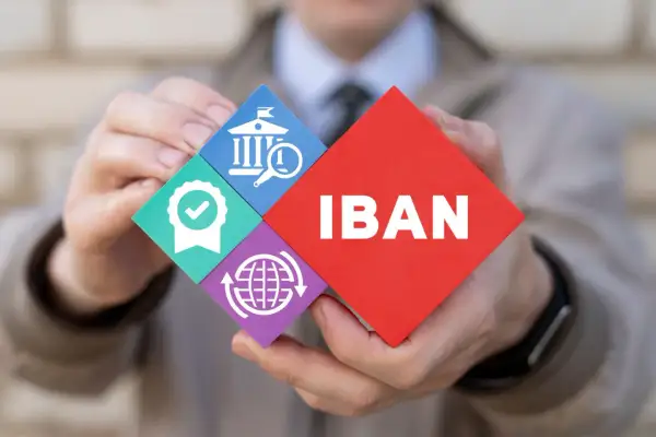Ręce trzymają puzzle z napisem IBAN i ikonami: bank, certyfikat, globalna sieć.