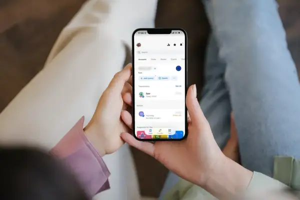Dłonie trzymają smartfon z aplikacją bankową, gdzie widać ostatnie transakcje, w tym zakup w Sparze. Można sprawdzić saldo i historię, unikając debetu.