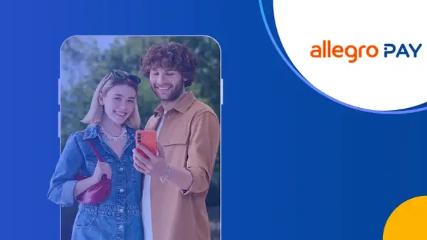 Uśmiechnięta para robi selfie telefonem. Na ekranie telefonu widoczna jest karta Allegro Pay, symbolizująca wygodne płatności.