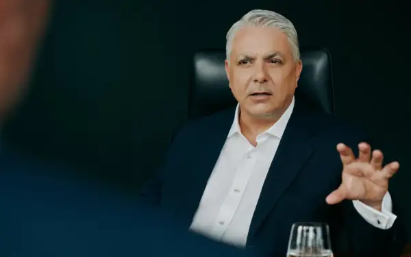 Mężczyzna w garniturze, członek Erste Group, gestykuluje podczas rozmowy.