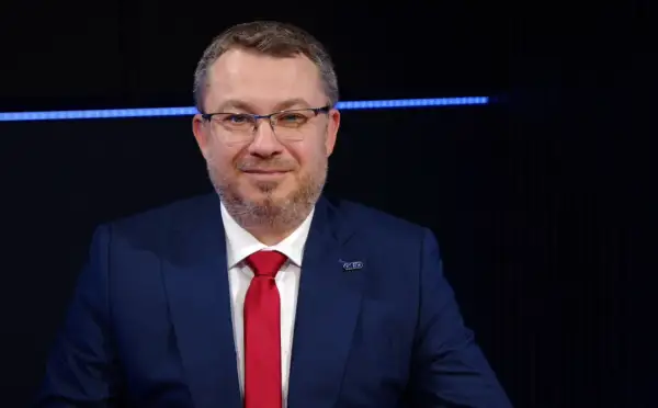 Mężczyzna w garniturze i czerwonym krawacie, z przypinką z logo. Może to być prezes Polimex Akcje.